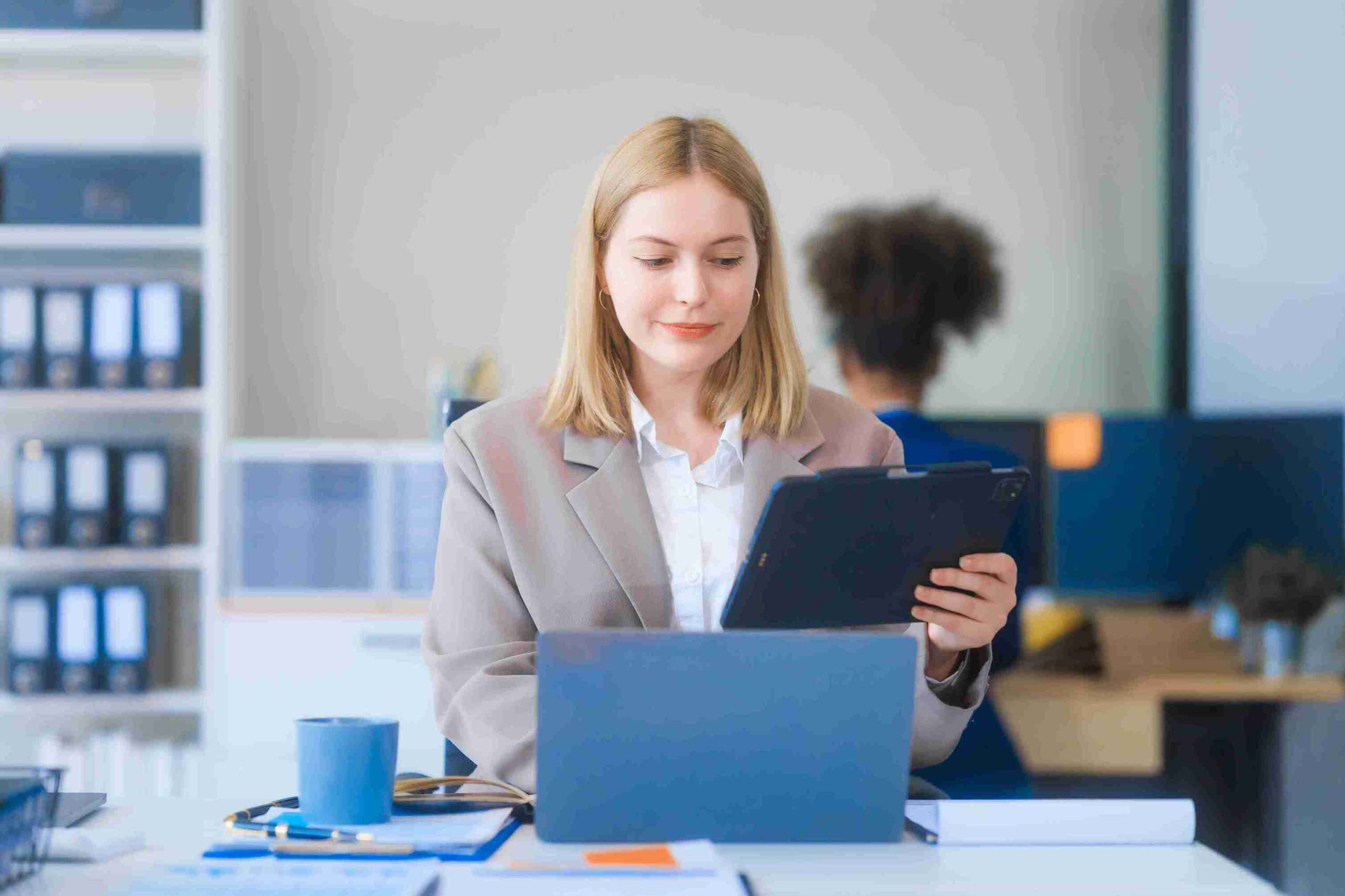 Businesswoman Working on Laptop While Holding a Digital Tablet